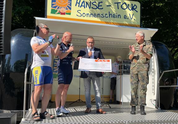 Die Fahrradkapitäne Frank Klaus und Stefan Gruhn (blaues Trikot) nahmen die Spende von SAS-Geschäftsführer Matthias Dankert entgegen. Auch der Kommandeur des Landeskommandos MV, Brigadegeneral Markus Kurczyk, gratulierte.