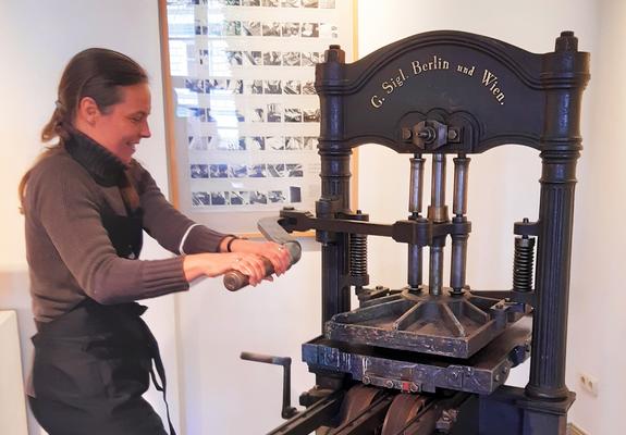 Sorgfalt und jede Menge Körpereinsatz sind nötig, um die 170 Jahre alte Druckerpresse in Bewegung zu bringen. Das kann Birgit Schattinger aus eigener Erfahrung bestätigen.