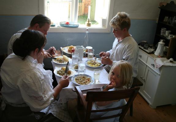 Eine Familie sitzt in der Häuslerei zum Essen zusammen, Foto: Freilichmtmuseum Mueß/Fred-Ingo Pahl