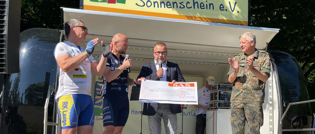 Die Fahrradkapitäne Frank Klaus und Stefan Gruhn (blaues Trikot) nahmen die Spende von SAS-Geschäftsführer Matthias Dankert entgegen. Auch der Kommandeur des Landeskommandos MV, Brigadegeneral Markus Kurczyk, gratulierte.