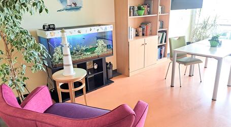 Die Bibliothek der Kurzzeitpflege „Friedensberg“  ist nebst Bücherregal, mit einer roten Couch und einem großen Aquarium gemütlich ausgestattet, Foto: Netzwerk für Menschen