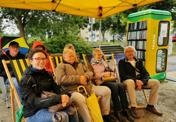 An der Tauschbox der WGS am Berliner Platz rückten die Zuhörer bei Regen zusammen und lauschten interessiert der Lesung von Schauspieler Martin Neuhaus aus „Bonnie Propeller”